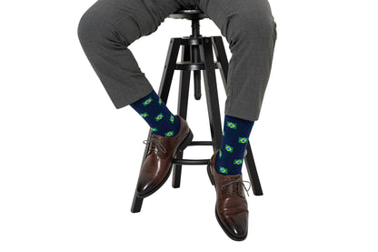 A man sitting on a stool wearing a pair of Brazil Flag Socks.