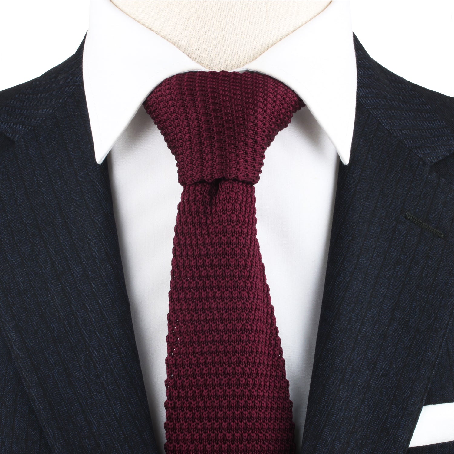 A close-up of a person wearing a dark pinstripe suit, a white dress shirt, and the Maroon Knitted Skinny Tie, exuding cozy elegance with the warm hues of the ensemble.