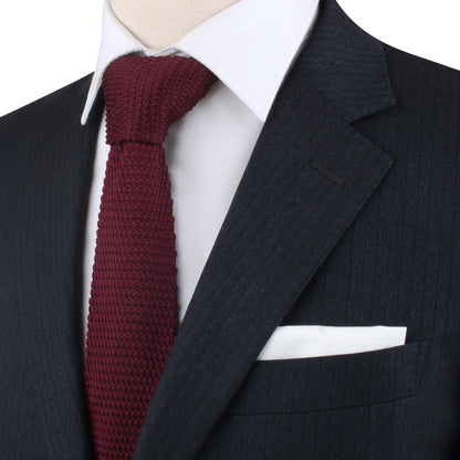 A close-up of a person wearing a dark pinstripe suit, white shirt, Maroon Knitted Skinny Tie, and white pocket square. The warm hues of the ensemble exude cozy elegance. Face is not visible.
