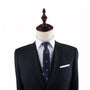 A tailored black suit on a mannequin exudes elegance, complemented by a white shirt and the Cake Slim Tie with a blue pattern against a plain white background.