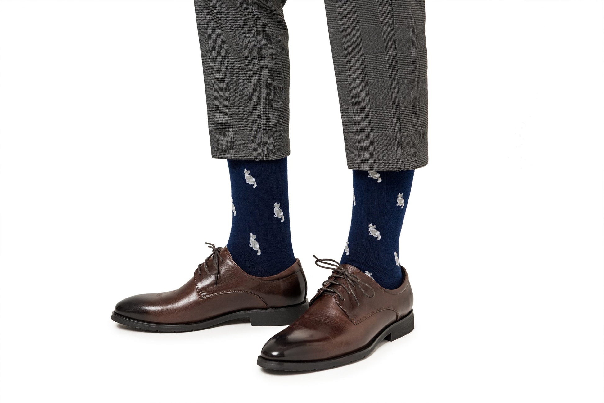 A pair of legs wearing brown shoes and Cat Socks.
