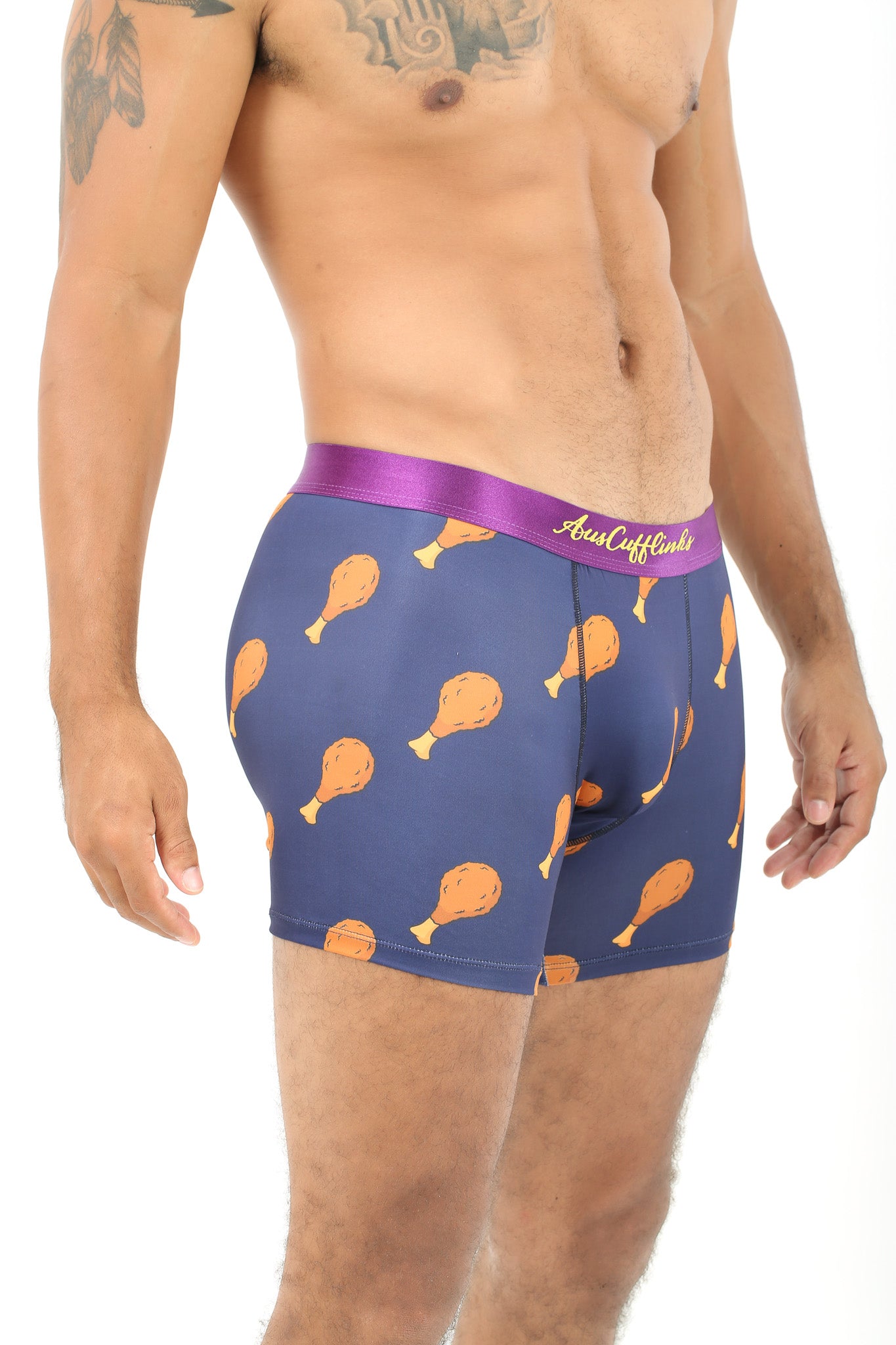 A person sporting Chicken Underwear features a fun chicken drumstick pattern on navy blue boxer briefs with a purple waistband, providing cuddly comfort.