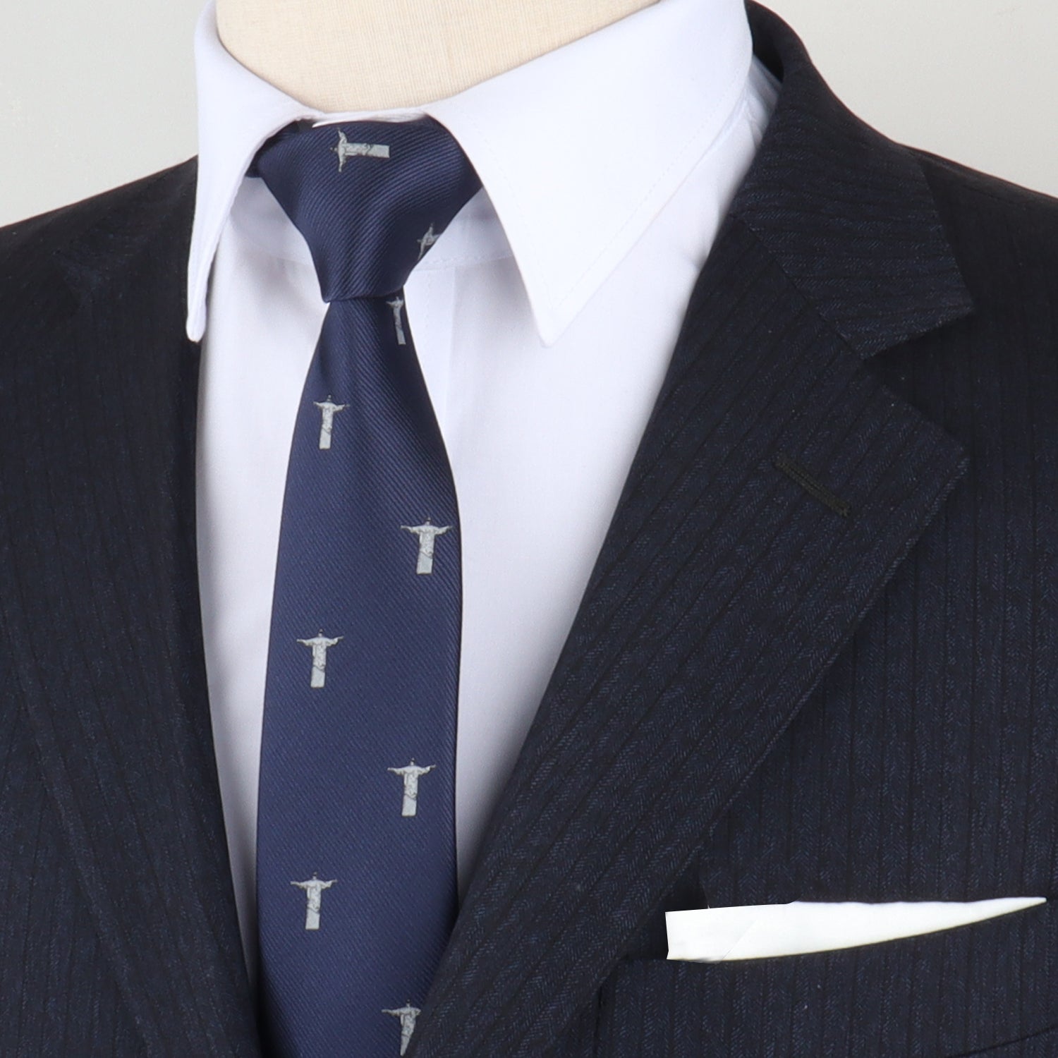 Close-up of a person wearing a dark pinstripe suit and white shirt, paired with the Christian Tie featuring small patterned designs, embodying a stylish form. A white pocket square is visible in the jacket pocket.