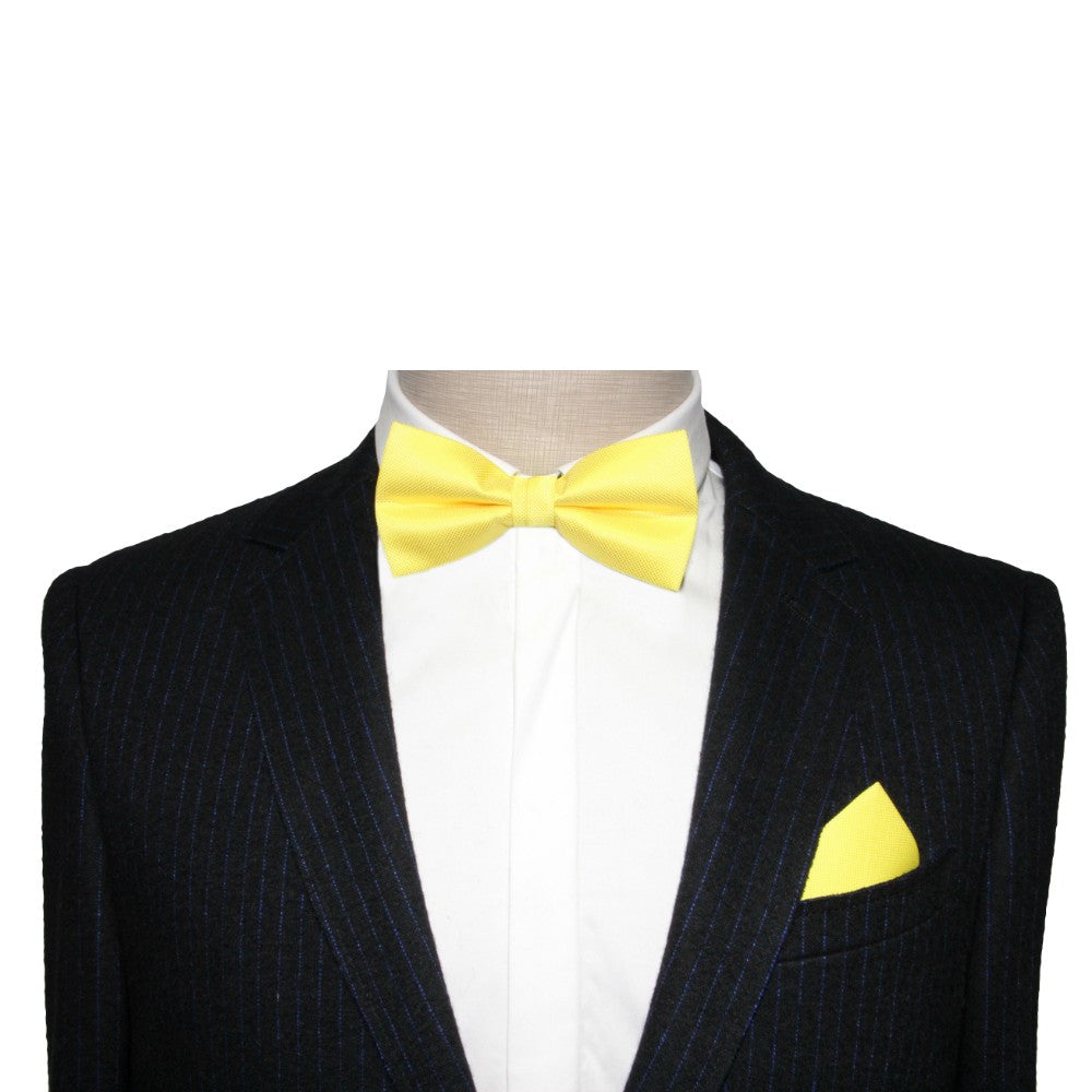 A mannequin dressed in a dark pinstriped suit with a white shirt, vivid lime green bow tie, and matching pocket square, making a bold statement.