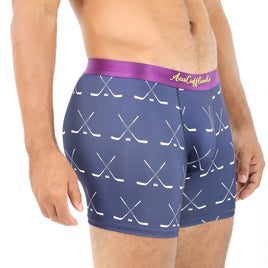 A man wearing the Crossed Ice Hockey Underwear, which features a stylish navy dual stick hockey pattern and a purple waistband, stands in a side pose to highlight both comfort and fashion.