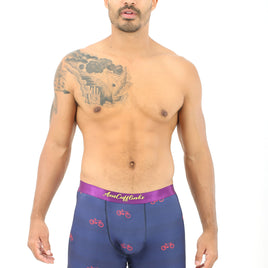 A man with tattoos standing in front of a cozy white background wearing Cyclist Boxer.