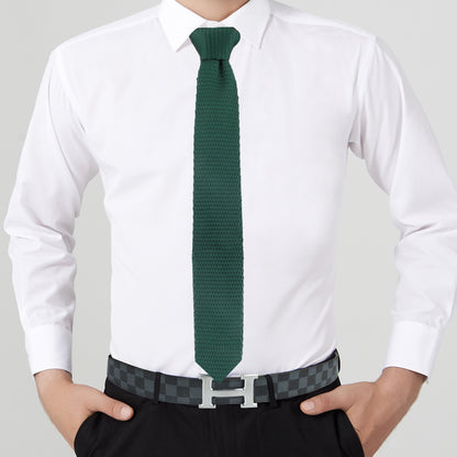 A person exuding elegance in a white dress shirt, Dark Green Knitted Tie, and black pants, accented by a checkered belt featuring a prominent silver "H" buckle.