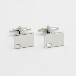Introducing the Diamante Silver Stone Cufflinks: a pair of rectangular silver cufflinks radiating elegance with small square embellishments, set against a shimmering white background.