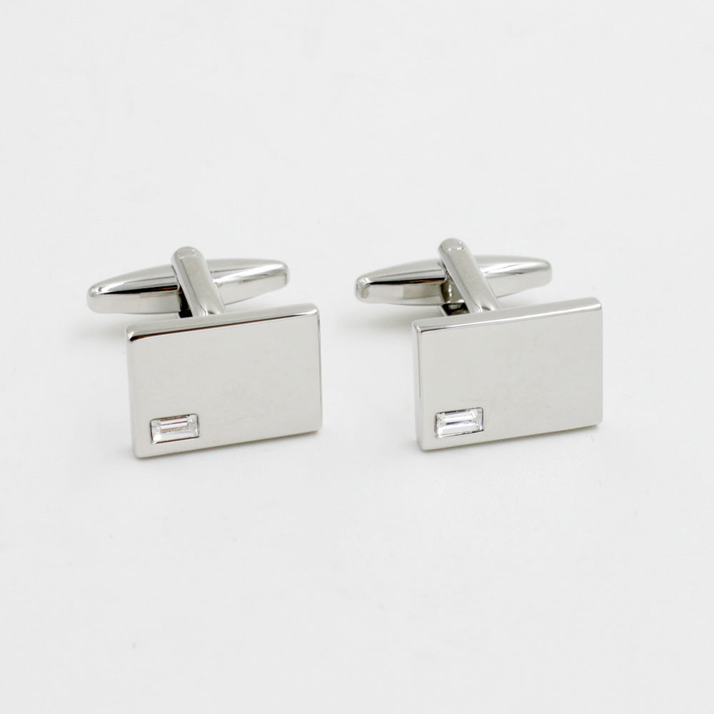 Introducing the Diamante Silver Stone Cufflinks: a pair of rectangular silver cufflinks radiating elegance with small square embellishments, set against a shimmering white background.