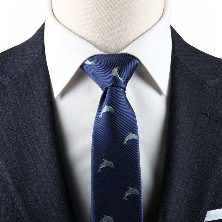 A person in a dark suit and white dress shirt is wearing a Dolphin Print Tie, perfect for ocean enthusiasts.