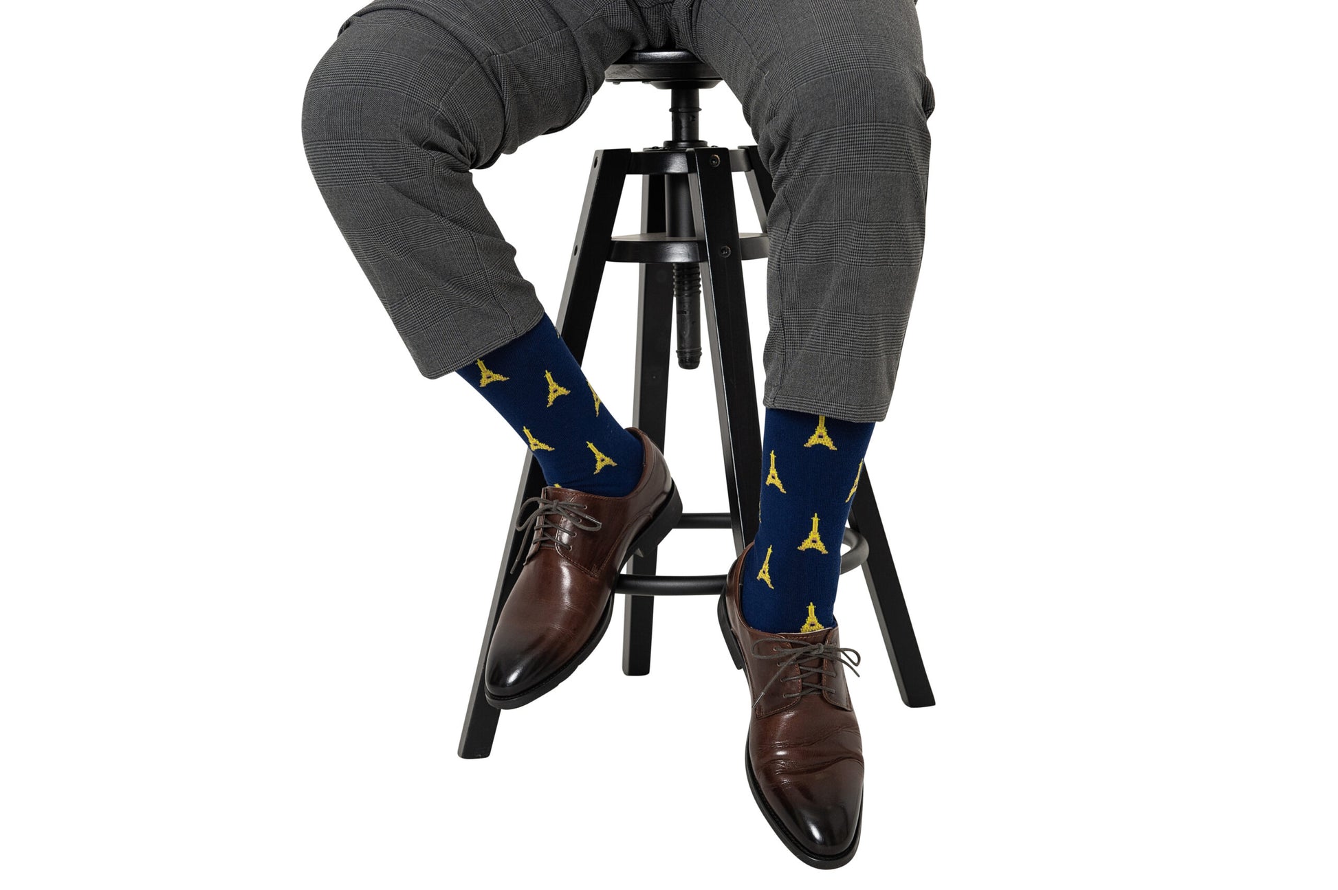 A man sitting on a stool wearing a pair of Eiffel Tower socks.
