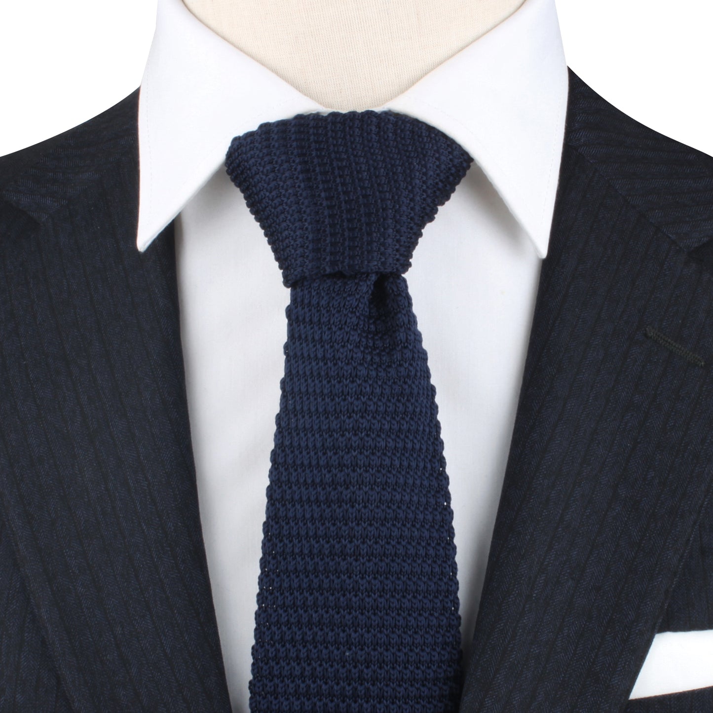 Close-up of a person wearing a dark pinstripe suit jacket, a white dress shirt, and a Formal Knit Tie, exuding elegance with its intricate weave pattern.