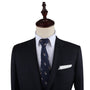 A suit on a mannequin stands tall, featuring a dark jacket, white dress shirt, and the Giraffe Print Tie with a subtle small animal print. Sophistication is elevated with the addition of a crisp white pocket square tucked into the breast pocket.