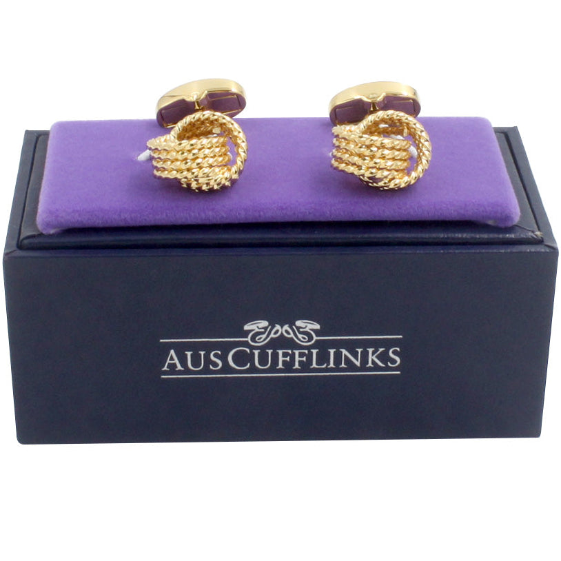 Gold Knot Premium Cufflinks for the discerning gentleman are elegantly displayed on a purple cushion atop a black box labeled "AUSCufflinks.