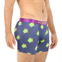 A person relishing the leisurely comfort of Green Turtle Underwear, featuring a blue hue with a charming turtle pattern and complemented by a purple waistband.