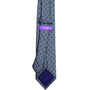 A gray tie adorned with small blue floral patterns exudes refined charm and features a purple inner label displaying the brand name "Astor & Black.