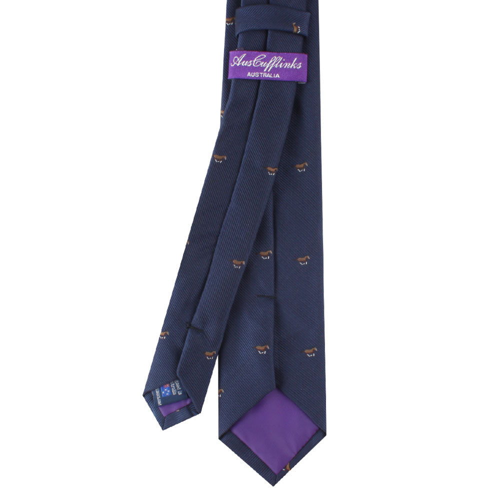 The Horse Motif Tie, featuring a navy blue design with a subtle brown pattern, boasts a purple fabric label inscribed with "Australia" and a matching purple lining on the underside, exuding elegance inspired by equestrian culture.