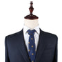 A navy suit jacket with a white dress shirt and the King Lion Slim Tie, adorned with gold lion motifs that symbolize courage, is displayed on a wooden mannequin against a plain, white background.