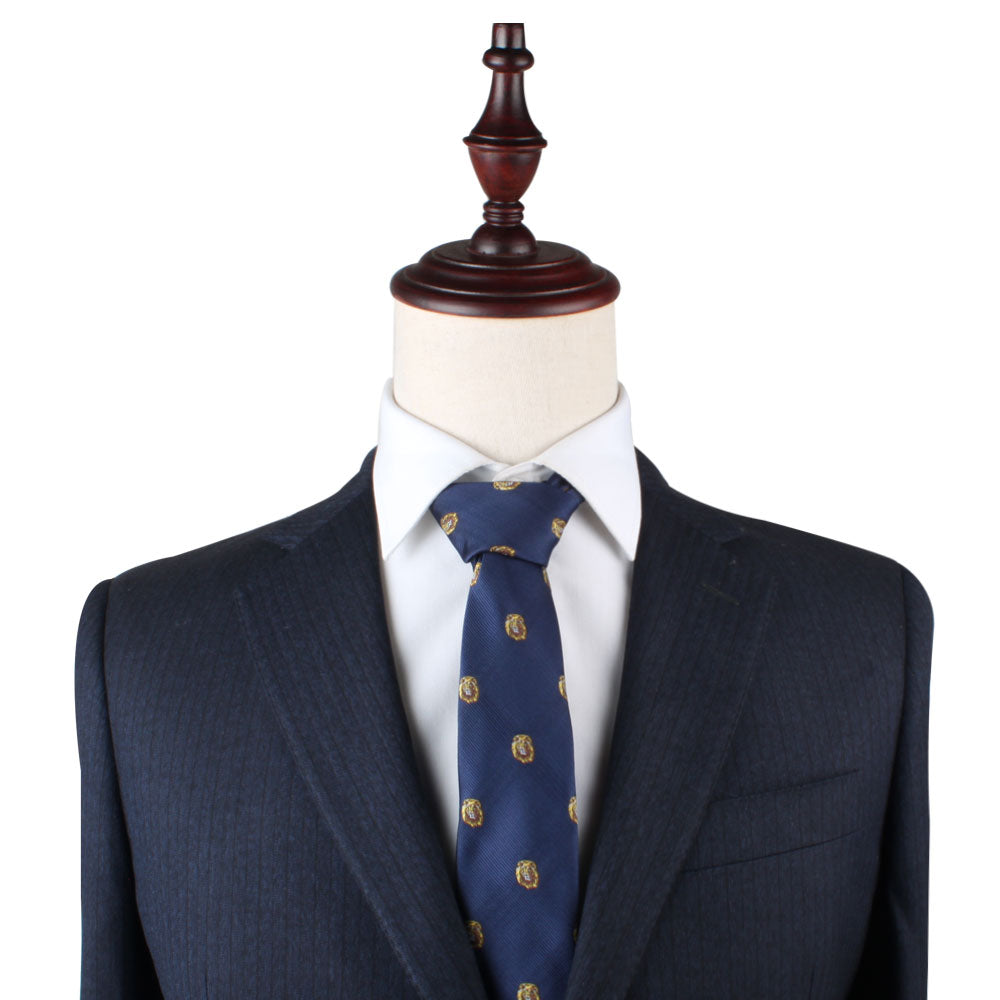 A navy suit jacket with a white dress shirt and the King Lion Slim Tie, adorned with gold lion motifs that symbolize courage, is displayed on a wooden mannequin against a plain, white background.