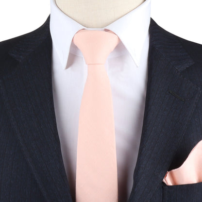 Close-up of a person wearing a suit with a white shirt, Baby Pink Skinny Tie, and matching pink pocket square woven with pastel threads, exuding charm.