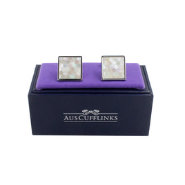 The Light Ocean Mosaic Cufflinks featuring a hexagonal pattern are elegantly placed on a purple cushion in a black "AUSCUFFLINKS" box. Ideal for the modern gentleman, these luxury cufflinks bring sophistication to any ensemble.