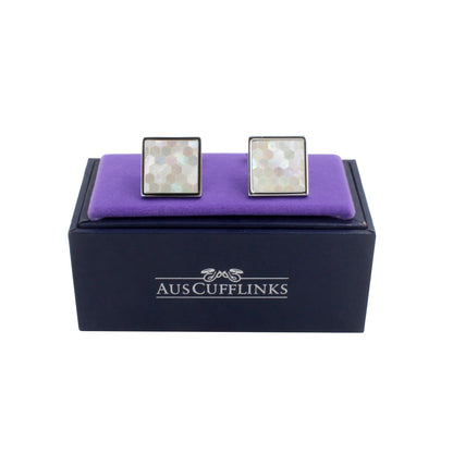 The Light Ocean Mosaic Cufflinks featuring a hexagonal pattern are elegantly placed on a purple cushion in a black "AUSCUFFLINKS" box. Ideal for the modern gentleman, these luxury cufflinks bring sophistication to any ensemble.