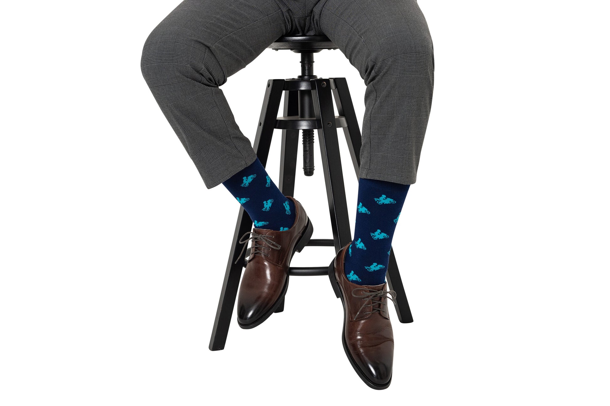 Man sitting on a barstool wearing grey pants, stylish brown dress shoes, and Motorbike Socks.