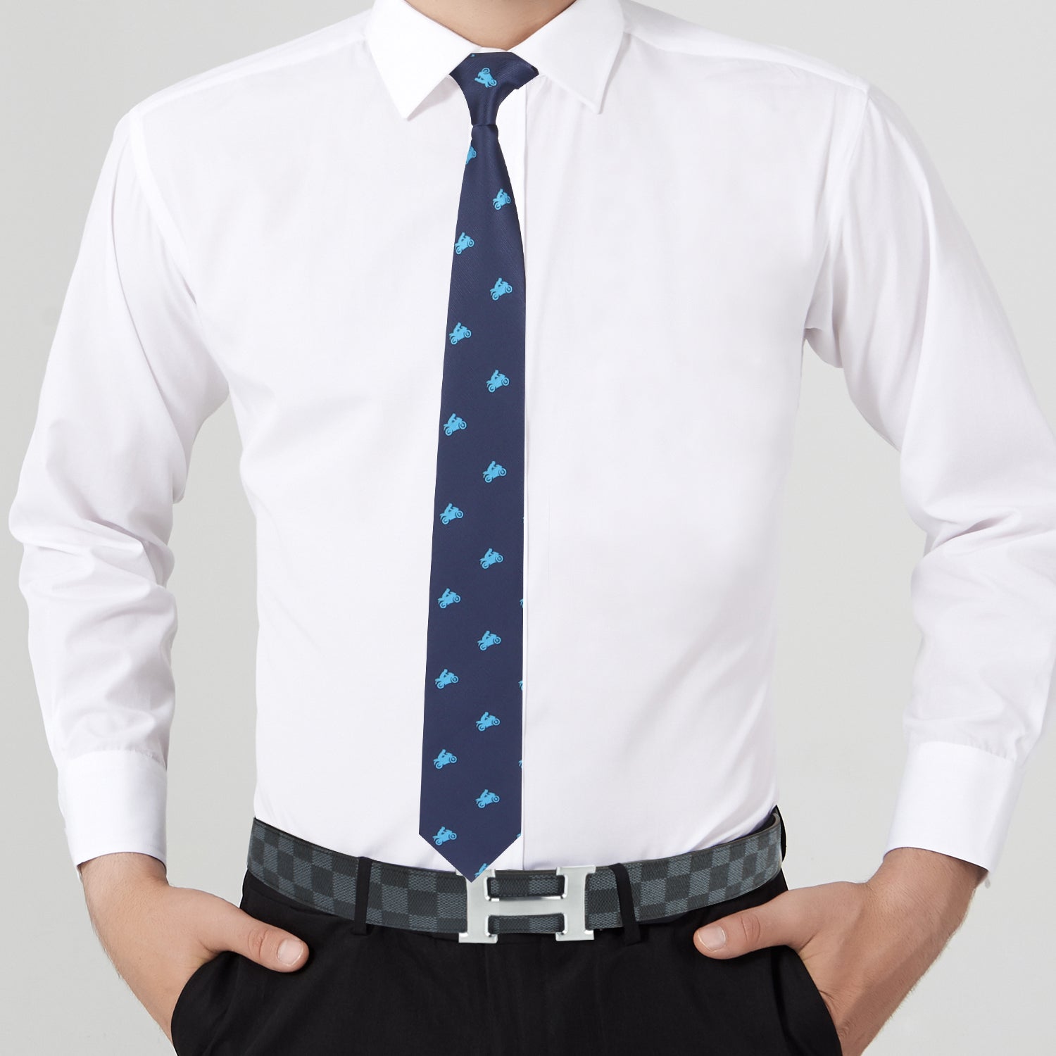 A person wearing a white dress shirt, a Motorbike Print Tie, black pants, and a bold black checkered belt with a metallic buckle stands with hands in pockets.
