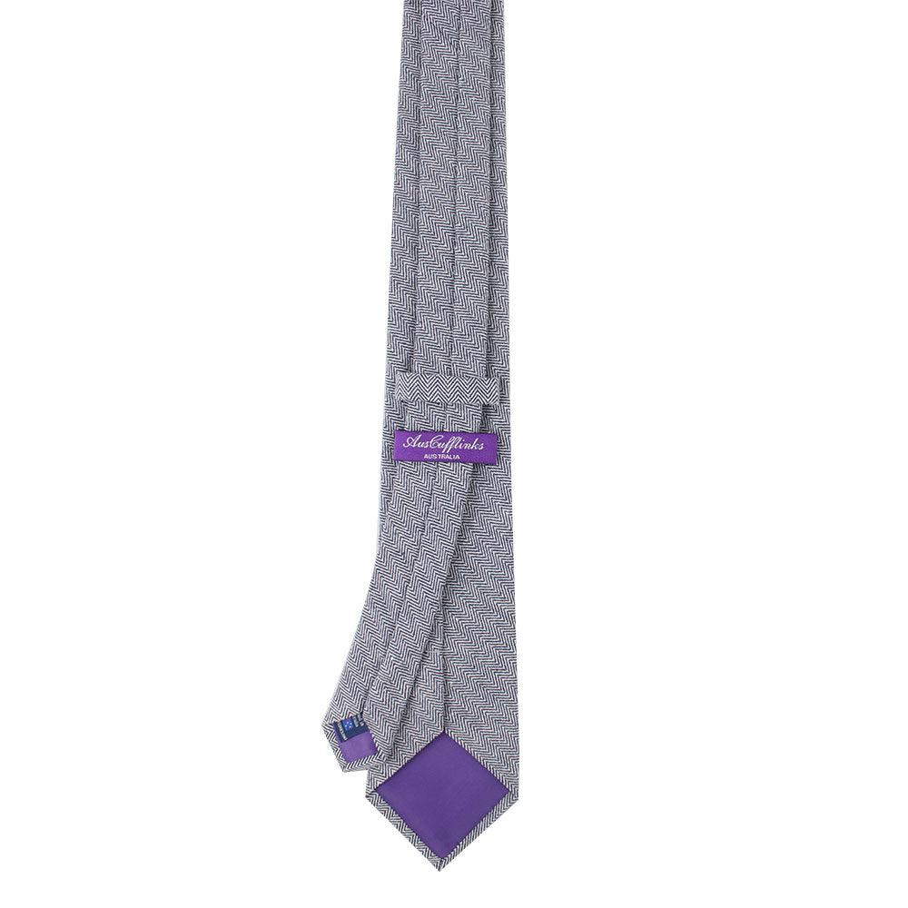 A Navy Blue Herringbone Business Cotton Tie, featuring a navy label and a purple triangular insert at the end for an extra touch of sophistication.