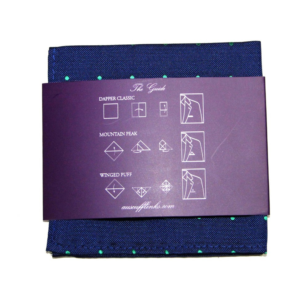 The Navy Green Polka Dot Business Tie & Pocket Square Set is designed for the modern gentleman, featuring a navy blue pocket square with green dots. It is elegantly wrapped with a purple band and illustrated instructions for three folding styles, perfectly complementing the tie.