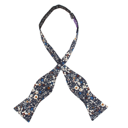 The Navy Multi Floral Self Tie Bow Tie features a vibrant floral pattern on dark fabric, perfect for weddings.