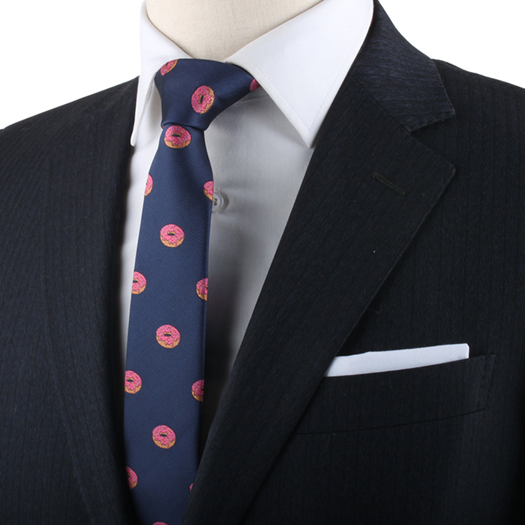 A close-up of a person wearing a dark suit, white shirt, and a Donut Skinny Tie engages in delectable style.