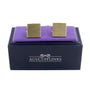 Opulent Gold Cufflinks are displayed on a purple cushion above a dark blue box with "AUSCUFFLINKS" written on it, showcasing an extravagant style.