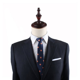 A mannequin dressed in a dark formal suit, white dress shirt, and an Orange Slim Tie exudes charm.