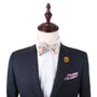 A mannequin exudes elegance in a dark suit jacket complemented by a Pastel Pink Rose Floral Bow Tie, floral pocket square, and rose lapel pin—ideal for weddings.