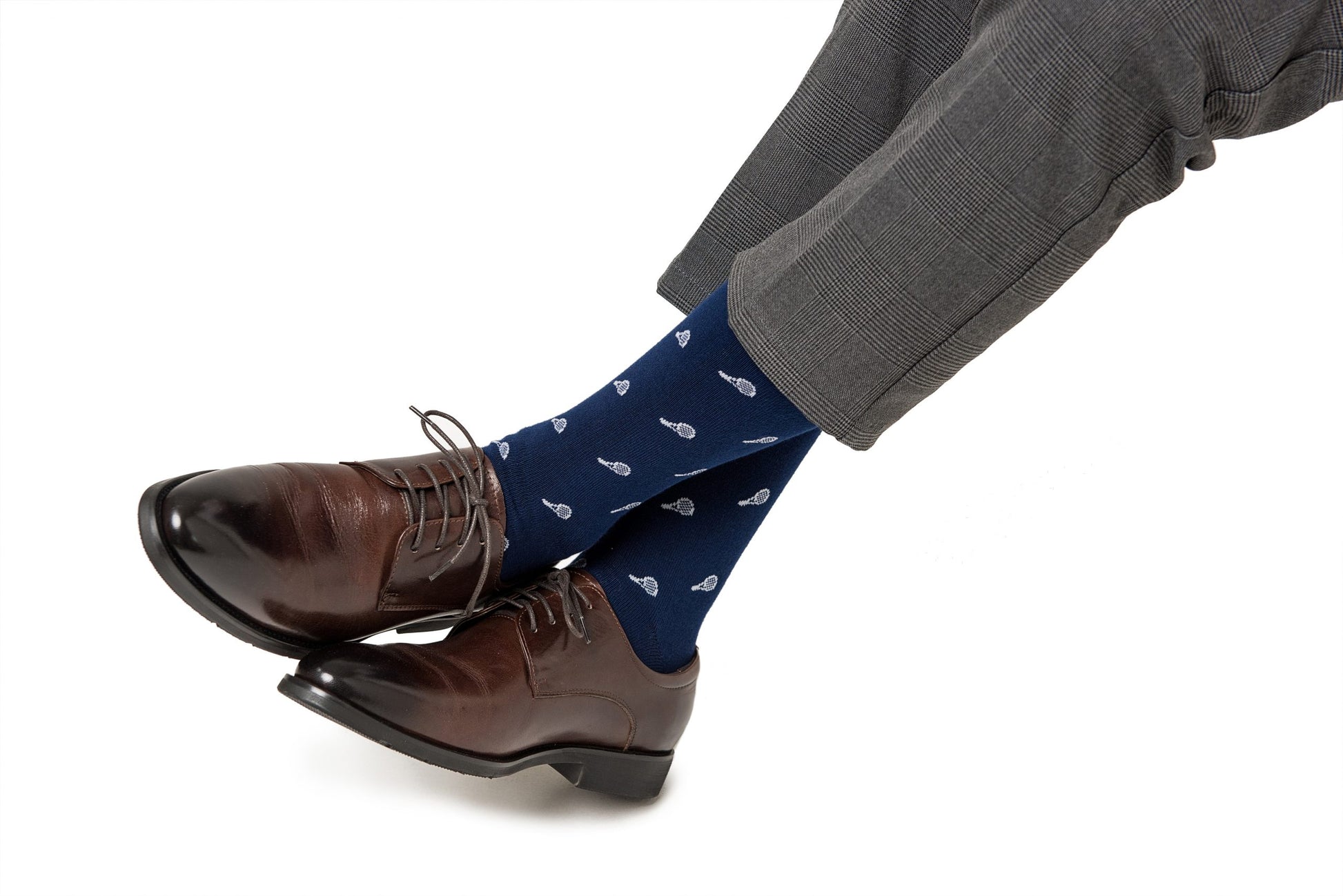 Person wearing gray checkered pants, Tennis Socks with small white designs, and brown leather dress shoes with gray laces for ultimate comfort during a high-performance day.