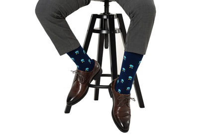 A person in gray plaid pants, brown dress shoes, and Table Tennis Socks sits on a black stool.