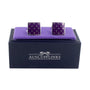 A pair of Tear Drop Purple Cufflinks on a purple display cushion exuding elegance, placed on a dark blue box labeled "AUSCUFFLINKS.