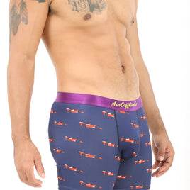 A person exudes coziness in Racing Car Underwear, featuring a stylish purple design with a vibrant small red airplane pattern, symbolizing speed. Their tattooed shoulder stands out against the crisp white background.