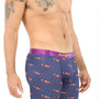 A person exudes coziness in Racing Car Underwear, featuring a stylish purple design with a vibrant small red airplane pattern, symbolizing speed. Their tattooed shoulder stands out against the crisp white background.