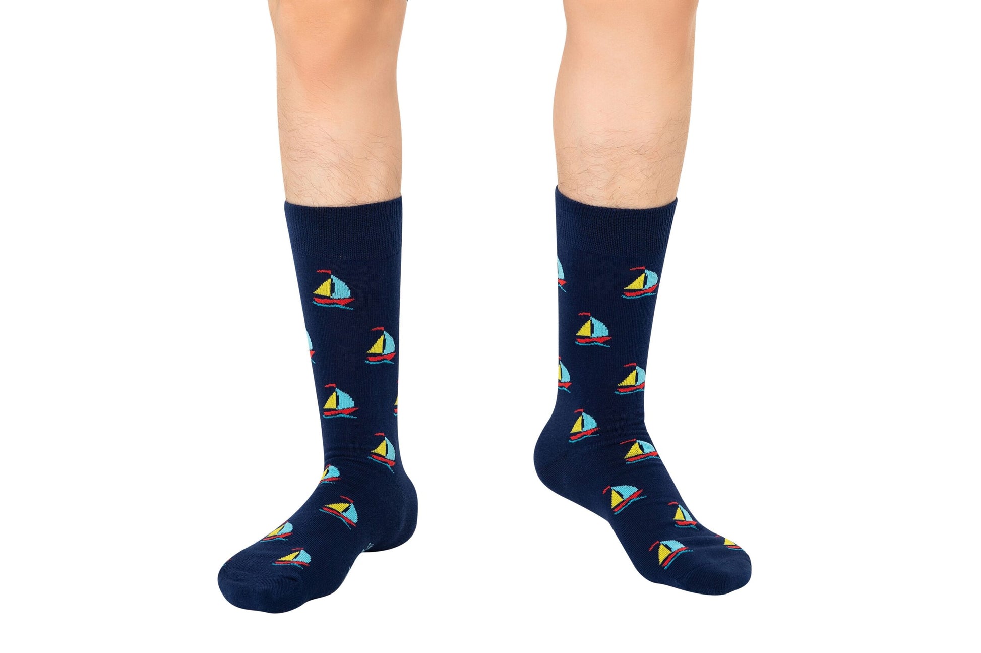 A person wearing Sail Boat Socks, showcasing colorful sailboat patterns against a dark blue background, evokes the comfort of sailing through gentle waves.