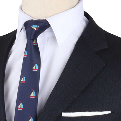 A close-up of a person wearing a dark pinstripe suit, white dress shirt, and a Sailboat Necktie. A white pocket square is visible in the suit jacket's breast pocket, adding to the overall nautical style.