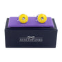 A pair of Sapphire Yellow Cufflinks radiates charm as they're displayed on a purple velvet cushion, placed on a black box labeled "AUSCUFFLINKS".