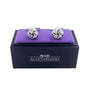 A pair of Silver Knot Cufflinks, exuding sophisticated style, rests on a purple cushion inside a sleek black AusCufflinks box.