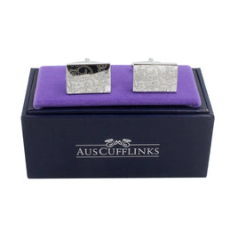 Paisley Cufflinks – Sleek & Modern Style for Men: Silver rectangular cufflinks with an engraved swirl pattern, presented on a purple cushion in a navy blue AUSCufflinks box—an ideal, sophisticated gift for him.