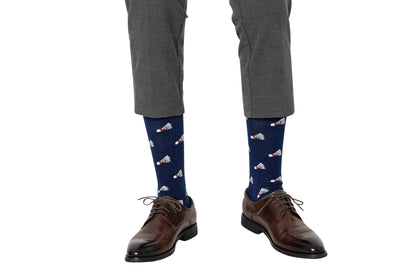 A person stands against a white background wearing gray plaid pants, brown dress shoes, and navy blue Badminton Socks featuring a moisture-wicking shuttlecock print.