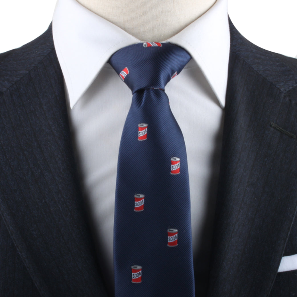 A person exudes refreshing style in a navy suit, complemented by a white shirt and a Soda Necktie adorned with small pop soda can designs.