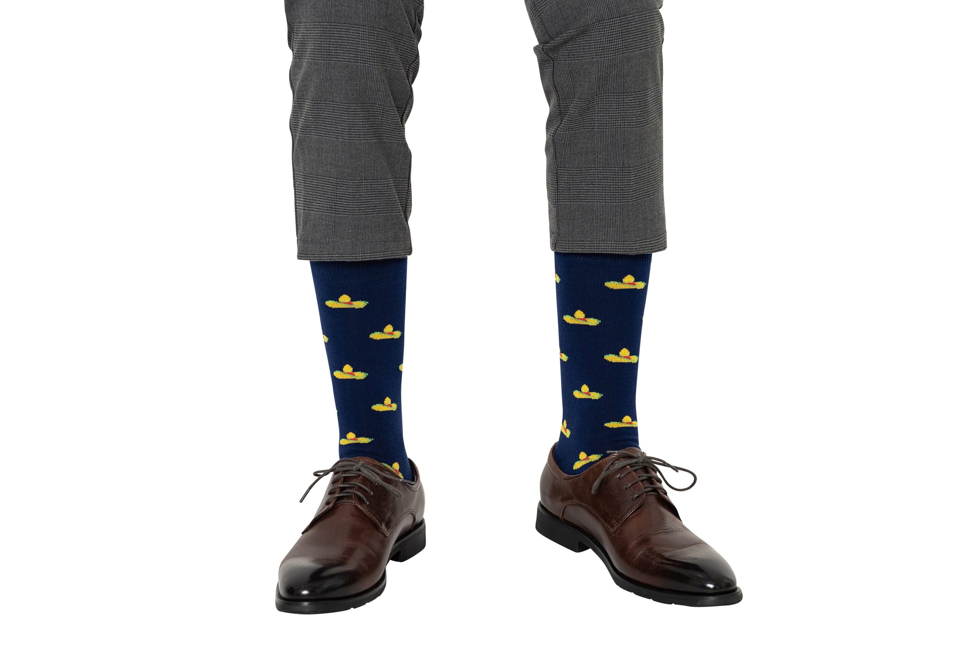 A person is dressed in gray pants, delightfully paired with brown footwear, and wearing Sombrero Socks adorned with a festive yellow rubber duck pattern.