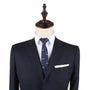 On a mannequin, a tailored navy suit showcases impeccable style with a white shirt, complemented by the Sombrero Slim Tie in navy adorned with small yellow patterns, and finished with a crisp white pocket square.