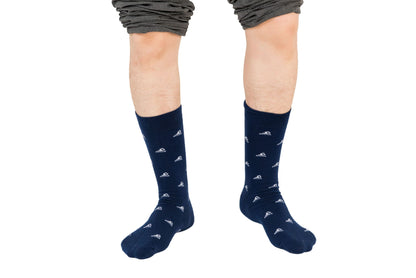 Two feet, clad in wave-washed style Swimming Socks in blue with small white patterns, stand confidently against a white backdrop, complemented by pants casually rolled up.